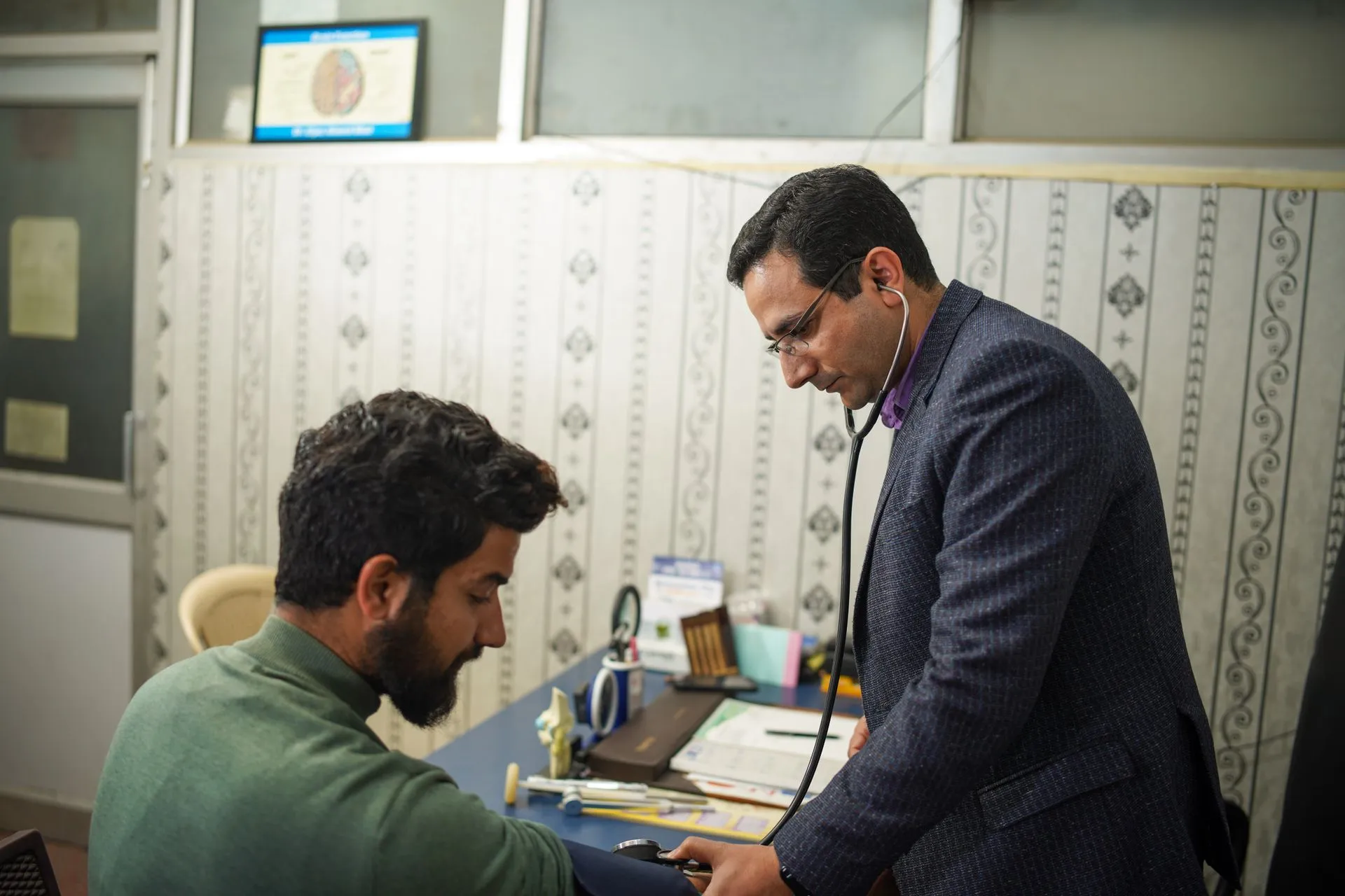 Doctor checking a patient's blood pressure with a stethoscope in a clinic